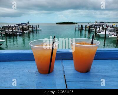 Boissons au rhum orange sur le pont bleu donnant sur la marina de Bimini, Bahamas l'après-midi d'été couvert. Banque D'Images