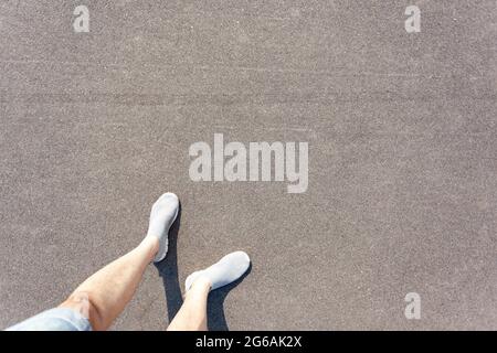Pieds pour hommes en short et chaussures sur l'asphalte, vue d'en haut Banque D'Images