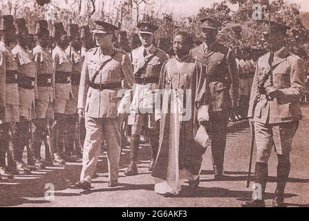 Mutesa II contourne la formation de soldats avec des représentants de l'administration britannique. Sir Edward Frederick William David Walugembe Mutebi Luwangula Mutesa II (1924 – 1969) était Kabaka du Royaume de Buganda en Ouganda du 22 novembre 1939 jusqu'à sa mort. Il était le trente-cinquième Kabaka de Buganda et le premier Président de l'Ouganda. La presse étrangère l'a souvent qualifié de roi Freddie, un nom rarement utilisé en Ouganda. Banque D'Images