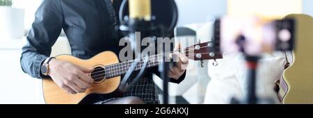Femme joue ukulele, et enregistre sur smartphone Banque D'Images