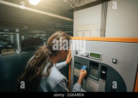 Man paie pour le parking souterrain dans le centre commercial dans une machine spéciale avec carte bancaire. Banque D'Images