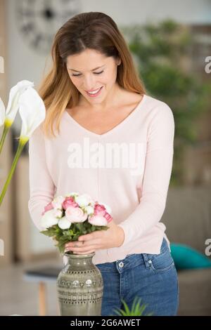 belle femme organisant des fleurs dans un vase Banque D'Images