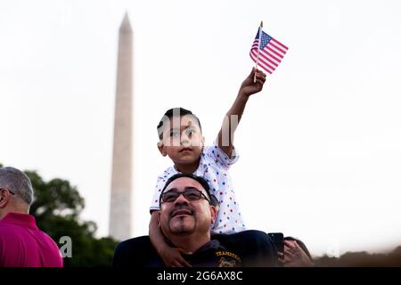 Washington, États-Unis. 04e juillet 2021. Gilbert Rodriguez, six ans de long Beach, Californie, détient le drapeau national américain sur les épaules de son père Eddie Rodriguez en tant que président américain Joe Biden prononce des remarques sur la pelouse sud de la Maison Blanche lors d'une célébration de la Journée de l'indépendance à Washington, DC, Etats-Unis, le 04 juillet 2021. Credit: SIPA USA/Alay Live News Banque D'Images