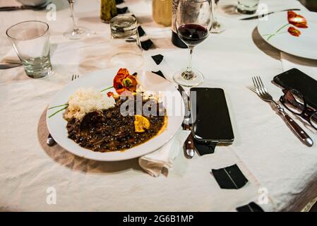 Plat brésilien typique appelé Feijoada. Fait de haricots noirs, de porc et de saucisse. Servi sur une assiette blanche pendant une réunion. Banque D'Images