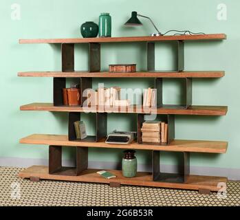 Étagère en bois rustique avec divers livres anciens et décorations rétro placés contre le mur vert à la maison Banque D'Images