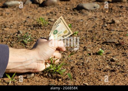Le poing d'un homme qui détient une note de dix dollars sur le sol. Investissement foncier, grand pari, concepts de projet de négociation Banque D'Images