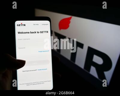 Personne tenant un smartphone avec le site Web de la plate-forme américaine de médias sociaux GETTR à l'écran devant le logo. Concentrez-vous sur le centre de l'écran du téléphone. Banque D'Images