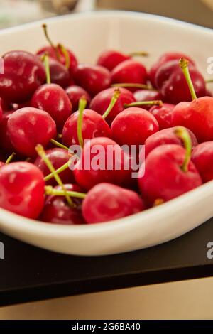 Cerises fraîches dans une assiette blanche, prêtes à manger Banque D'Images