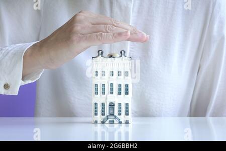 Maison appartement miniature couverte à la main. Concept d'assurance de biens. Banque D'Images