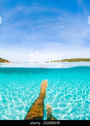 (Mise au point sélective) vue imprenable sur une personne nageant dans une eau turquoise et claire. Demi-mer sous-marine et demi-bleu ciel image. Banque D'Images