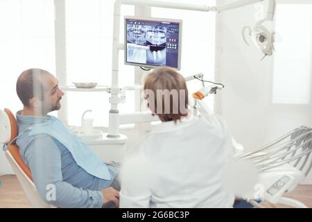 Dentiste médecin et patient regardant la radiographie numérique de teeh dans le bureau de l'hôpital de stomatologie. Patient malade assis sur une chaise dentaire se préparant à la chirurgie dentaire pendant un rendez-vous de somatologie Banque D'Images