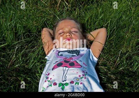 Vue en hauteur d'une fille qui se trouve dans un pré sous le soleil d'été, Pologne Banque D'Images