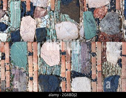 Texture du mur avec des blocs de pierre de couleurs rouge, jaune, vert et gris. Arrière-plan horizontal avec mosaïque décorative en pierre Banque D'Images