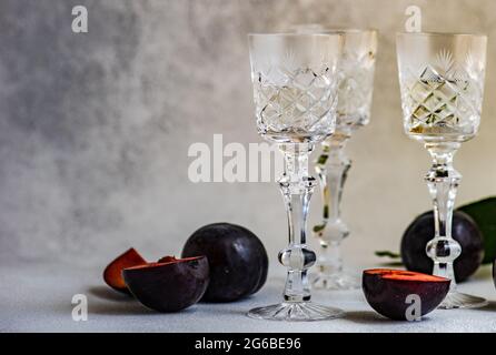 Trois verres de vodka à la prune sur une table avec des prunes fraîches Banque D'Images