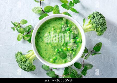 Soupe verte végétalienne avec ingrédients. Brocoli, pois verts et feuilles de menthe fraîche, tiré par le haut. Menu de désintoxication printanier sain. Régime biologique de légumes Banque D'Images