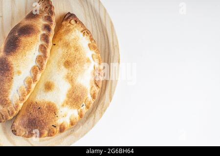 Délicieux empanadas argentins sur un panneau en bois sur fond blanc avec espace pour le texte Banque D'Images