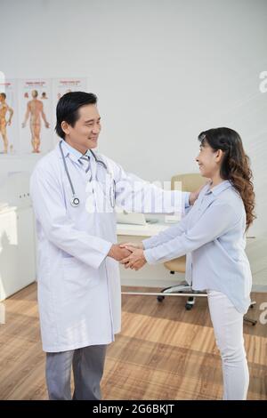 Une femme heureuse et reconnaissante qui secoue la main de son médecin lui montrant son appréciation Banque D'Images