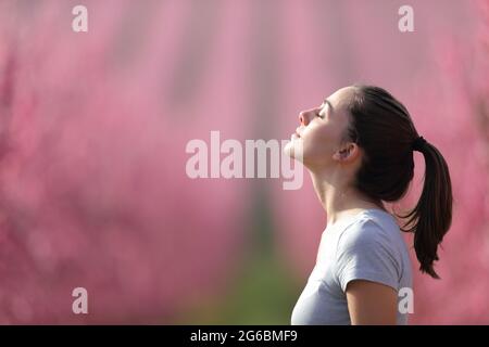 Vue latérale d'une femme qui respire de l'air frais dans un champ rose après le sport