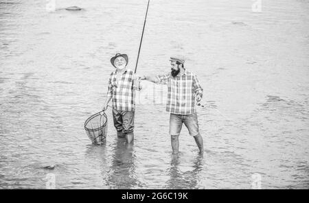 travaillez en équipe. escapade rurale. loisir. nature sauvage. deux pêcheurs heureux avec canne à pêche et filet. Camping sur la rive du lac. Père et fils pêche Banque D'Images