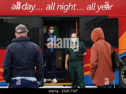 Les membres du public font la queue devant un bus de vaccination contre les covidés au centre commercial Forge de Glasgow. L'unité mobile de vaccination dirigée par le Scottish Ambulance Service visitera les communautés locales et les centres urbains très fréquentés d'Edimbourg et de Glasgow pendant deux semaines. Date de la photo: Lundi 5 juillet 2021. Banque D'Images