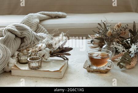 Verre de thé, élément tricoté et fleurs séchées à l'intérieur de la chambre. Banque D'Images