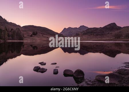 Coucher de soleil à Blea Tarn en direction des Langdale Pikes dans le parc national du Lake District. Banque D'Images