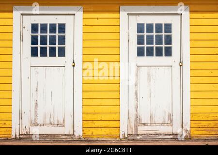 Portes en bois blanc sur les cabines de plage jaunes Banque D'Images