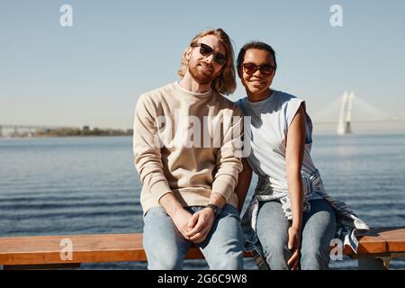 Portrait de jeune couple contemporain regardant l'appareil photo tout en posant par la rivière à l'extérieur, espace de copie Banque D'Images