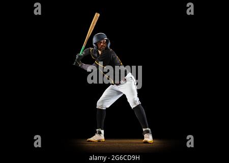 Joueur de baseball professionnel, pichet en uniforme de sport et équipement de pratique isolé sur fond noir de studio. Concept de sport d'équipe Banque D'Images