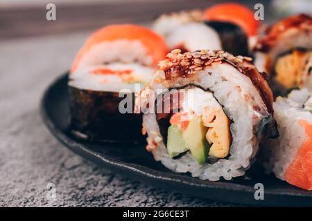 Vue rapprochée des petits pains à sushi avec saumon, avocat et anguille en béton sur le fond de la table - futomaki. Uramaki, hosomaki. Commander des aliments en ligne et Banque D'Images