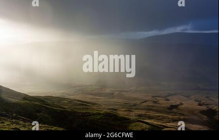 Soleil qui brille à travers les nuages de pluie lors d'une journée d'hiver, Wensleydale, North Yorkshire, Royaume-Uni. Banque D'Images