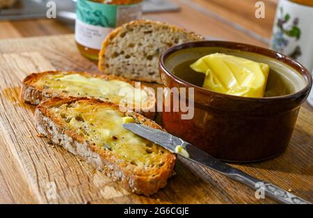 Pain grillé au beurre pour le petit déjeuner sur une planche de bois Banque D'Images