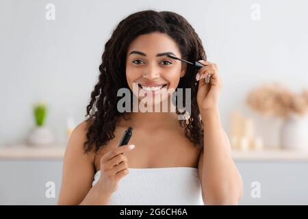 Femme se préparer pour le travail, faisant le maquillage matin routine dans la salle de bains à la maison Banque D'Images