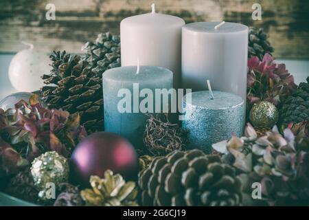 Couronne de l'AVENT avec quatre bougies différentes dans des couleurs colorées et décoration naturelle Banque D'Images