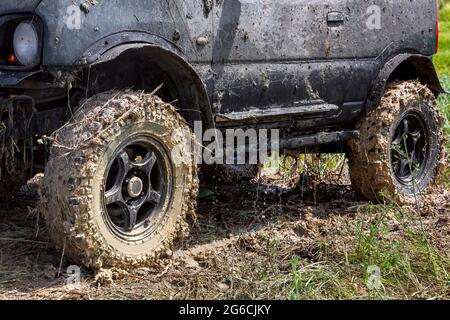 Vus noir avec de grandes roues sales dans un marais se tient sur l'herbe, l'eau s'écoule du corps après avoir été inondée dans la rivière, vue de côté, non Banque D'Images