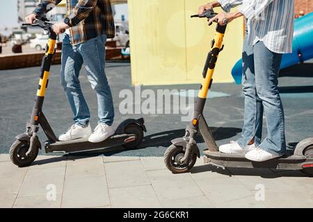 Prise de vue rognée d'un jeune couple utilisant des scooters électriques tout en conduisant dans les rues de la ville, espace de copie Banque D'Images