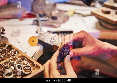 Personne dans l'atelier de bijoutier tenant le modèle de bague mauve Banque D'Images