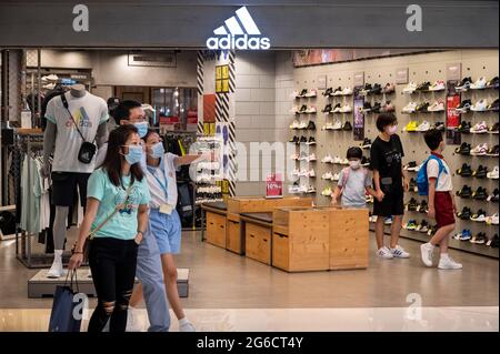 Hong Kong, Chine. 05e juillet 2021. Une famille passe devant le magasin et le logo Adidas de la marque allemande multinationale de vêtements de sport à Hong Kong. Crédit : SOPA Images Limited/Alamy Live News Banque D'Images