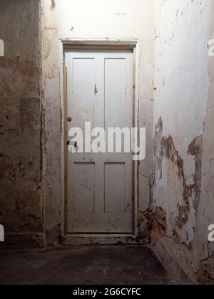 Ancienne porte intérieure en bois, verrouillée, dans un couloir sombre dans une vieille maison abandonnée. Banque D'Images