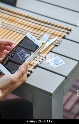 De dessus de récolte mâle non reconnaissable à l'aide d'un smartphone et de la lecture du code QR du menu du restaurant Banque D'Images