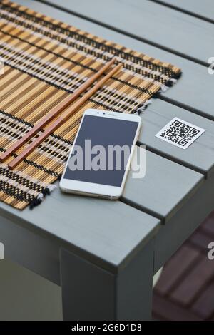 Depuis le dessus du téléphone portable placé sur la table avec le code QR du menu du restaurant Banque D'Images