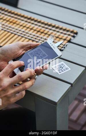 De dessus de récolte mâle non reconnaissable à l'aide d'un smartphone et de la lecture du code QR du menu du restaurant Banque D'Images