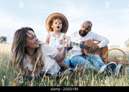 Nous avons ravi toute la famille multiraciale en dégustant un pique-nique ensemble tout en dégustant des en-cas et en jouant de la guitare dans la nature Banque D'Images