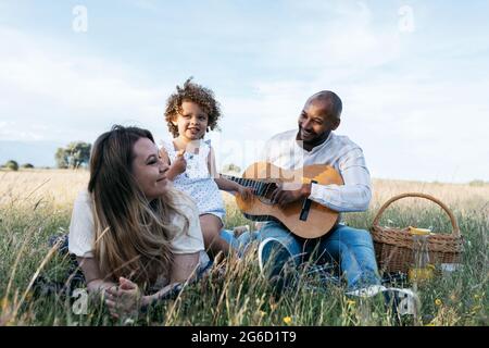 Nous avons ravi toute la famille multiraciale en dégustant un pique-nique ensemble tout en dégustant des en-cas et en jouant de la guitare dans la nature Banque D'Images