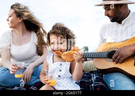 Nous avons ravi toute la famille multiraciale en dégustant un pique-nique ensemble tout en dégustant des en-cas et en jouant de la guitare dans la nature Banque D'Images
