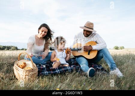 Nous avons ravi toute la famille multiraciale en dégustant un pique-nique ensemble tout en dégustant des en-cas et en jouant de la guitare dans la nature Banque D'Images