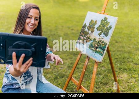 Femme effectuant un appel vidéo pour montrer une peinture à l'extérieur Banque D'Images