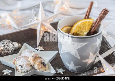 Tasse de thé ou de punch et mini Stollenon plateau en bois sur une couverture blanche, décoré avec boule de noël, petites étoiles et étoiles de fée lumières Banque D'Images