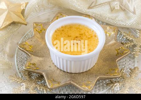 Crème brûlée - dessert traditionnel à la crème vanille française avec sucre caramélisé sur une assiette en forme d'étoile dorée et décoration de noël dorée Banque D'Images