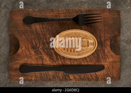 De dessus planche à découper rayée avec fourchette et boîte scellée avec des aliments conservés sur table de bois rustique Banque D'Images